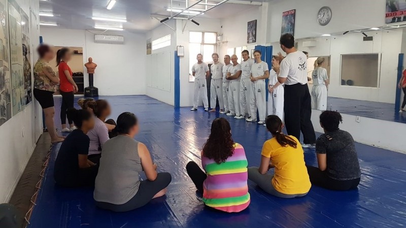 Defensoria Pública desenvolve projeto-piloto de defesa pessoal para mulheres vítimas de violência de gênero. Na foto, mulheres estão sentadas ouvindo as explicações dos professores
