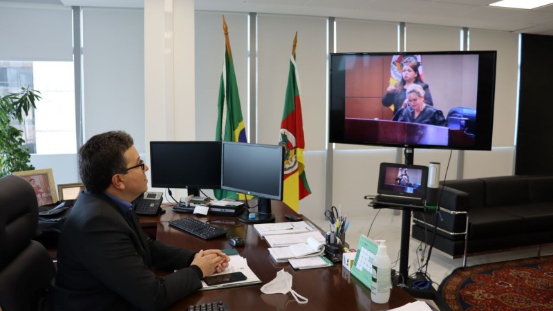 Defensor Público-Geral olha para tela e acompanha transmissão da posse dos novos Desembargadores. 