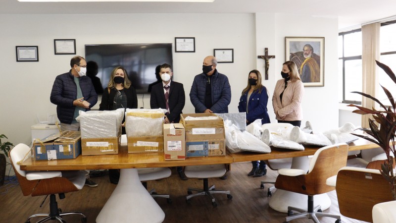 PREFEITO, SUBDEFENSORA, DEFENSOR DE OSÓRIO, SECRETÁRIO DE EDUCAÇÃO E DUAS SERVIDORAS POSANDO COM OS EQUIPAMENTOS EM CIMA DE UMA MESA