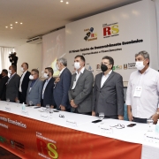 mesa de abertura do evento, com autoridades cantando o hino nacional