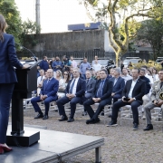 chefe de polícia no palco, em primeiro plano e de costas, discursando para o público que estava sentado