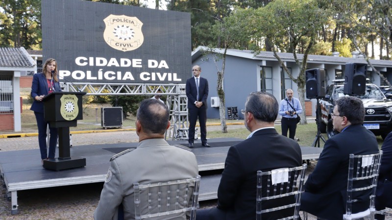 chefe de polícia no palco, em segundo plano e de frente, discursando para o público que estava sentado