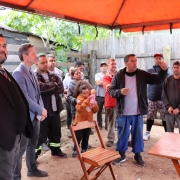 imagem dos catadores reunidos em um terreno baldio, embaixo de um gazebo laranja, com dois defensores, e um dos catadores discursando