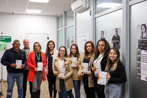 grupo de 9 pessoas, em um semi círculo, posando paara a foto e segurando as cartilhas sobre luto parental