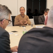 em primeiro plano e nos cantos da foto, desfocados, estão 2 participantes da reunião. Em segundo plano, entre eles e focado, está o juiz alexandre, que fala para os demais