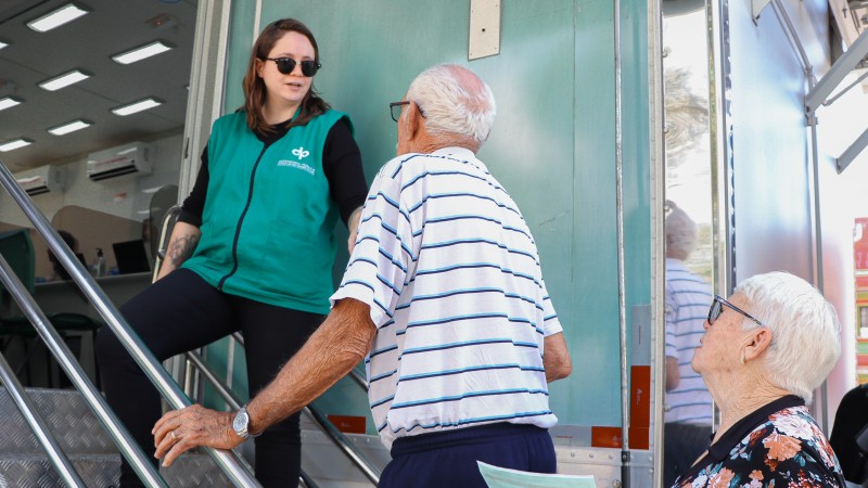 Servidora recebendo um casal idosos no veículo da Defensoria Itinerante