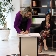 Foto da dirigente do NUDECA, Andreia Paz Rodrigues, assinando o termo de cooperação 