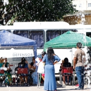 mutirão acontece ao fundo, gotas de água do sistema de irrigação aparecem em desfoque na tela