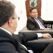imagem do defensor geral de costas, em primeiro plano e desfocado, e o senador hamilton mourão de frente, em segundo plano, e focado, olhando para o defensor geral