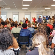 Auditório do prédio-sede com muitas pessoas. Defensora pública Alessandra Quines falando