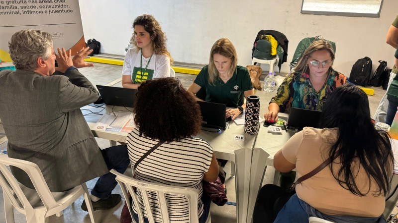 foto geral do atendimento da defensoria no mutirão. são três pessoas atendendo outras três pessoas. por cima da foto, os dizeres Mais de 10 mil atendimentos são registrados na Central Cidadania do Shopping Total, que contou com participação da DPE/RS