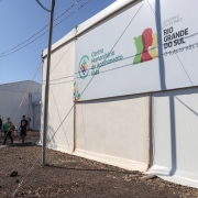Entrada do Centro Humanitário de Acolhimento Vida. Em segundo plano na foto, há pessoas caminhando 