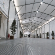 Parte interna do Centro Humanitário de Acolhimento; um longo corredor em que se veem árvores plantadas em vasos e portas de entrada para as alas de alojamento