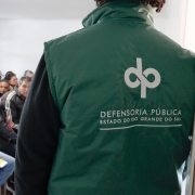 Servidor em primeiro plano, ao fundo público espera por atendimento.