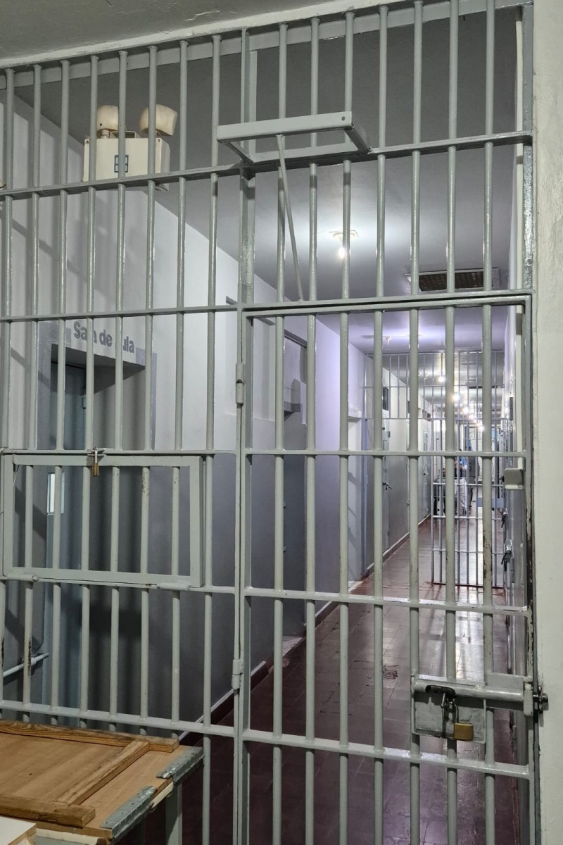 Foto geral de um corredor com sala de aula e uma grade