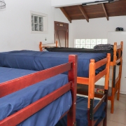 Quarto com 3 beliches, ventilador, janela, armário.