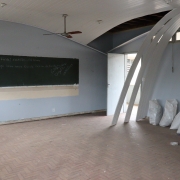 Sala de aula com o teto caído e materiais de construção ensacados