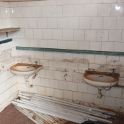 Banheiro com pias na altura do uso de crianças, sujo, destruído, por conta das enchentes de maio