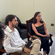 3 pessoas sentadas a uma mesa em uma sala, olhando para alguém que não aparece na foto