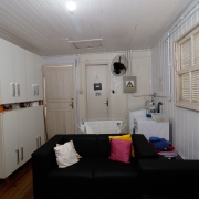 foto do interior da casa de madeira, com dois sofás, alguns armários, máquina de lavar roupa e um varal de chão