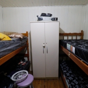 foto de um dos quartos, com dois beliches, um em cada lado, e um armário no meio deles