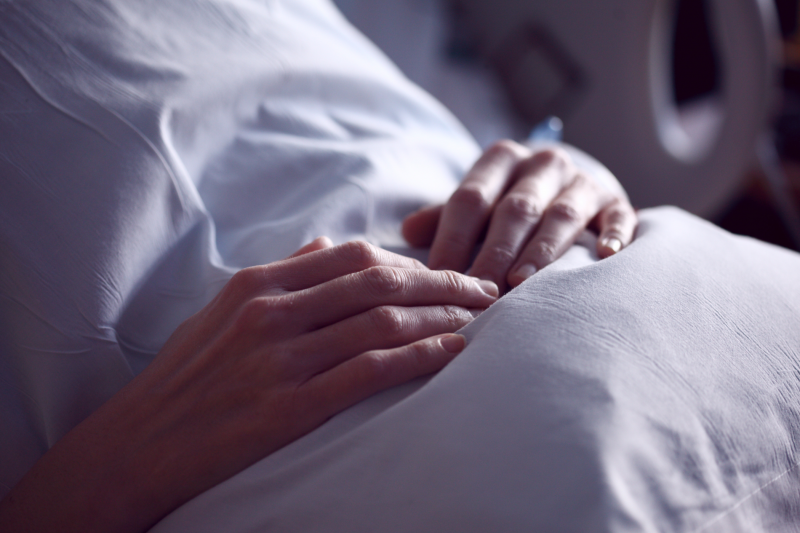 Paciente em cama de hospital com as mãos na barriga.
