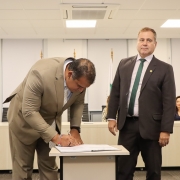 foto do ouvidor assinando sua posse e o defensor geral do lado, em pé, acompanhando