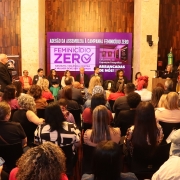 foto geral do evento, tirada ao fundo, pegando o público de costas e de frente a deputada que discursava