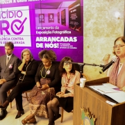 foto da ministra das mulheres discursando em um púlpito. Ao seu lado, as autoridades que estavam sentadas à frente