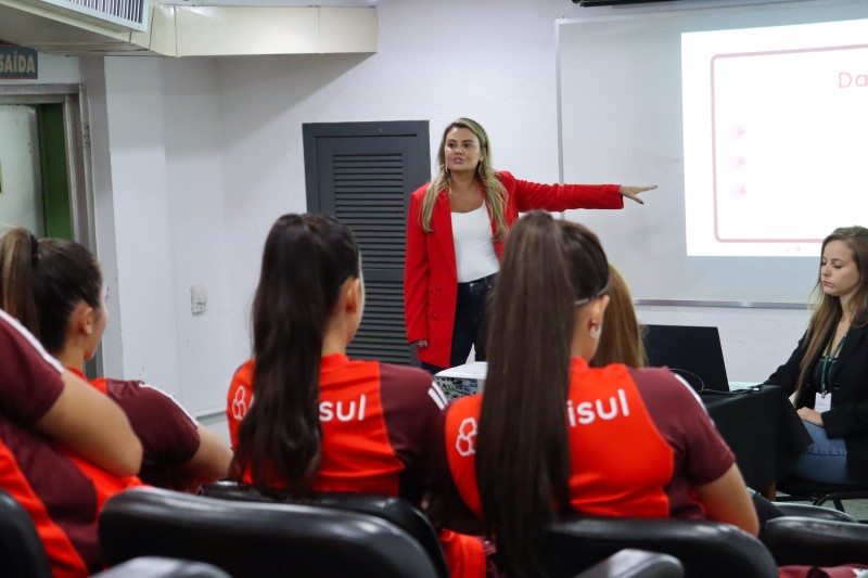 Atletas da categoria de base das Gurias Coloradas assistindo a uma palestra sobre assédio e violência de gênero.
