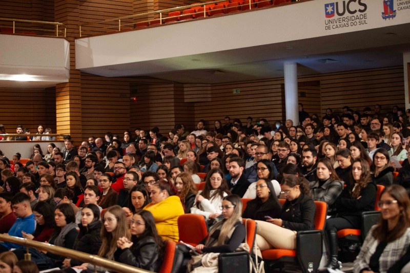 Na foto, vemos os estudantes acompanhando o evento na Universidade.