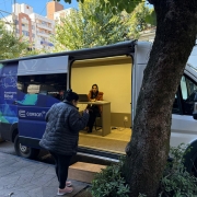 Na foto, vemos uma senhora em frente à van da CORSAN.