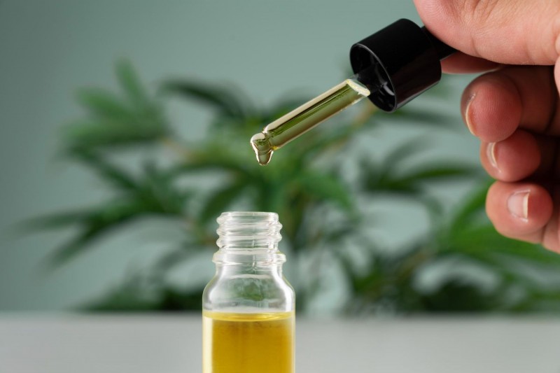Folha de Cannabis sativa e recipiente de &oacute;leo CBD com tampa conta gotas 