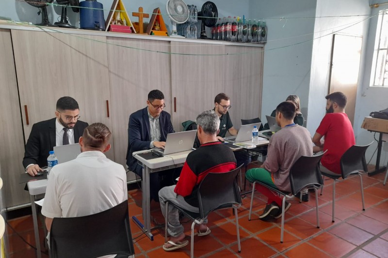 Na foto, h&aacute; defensores p&uacute;blicos atendendo quatro homens que est&atilde;o presos na Penitenci&aacute;ria Estadual de Santo Cristo.