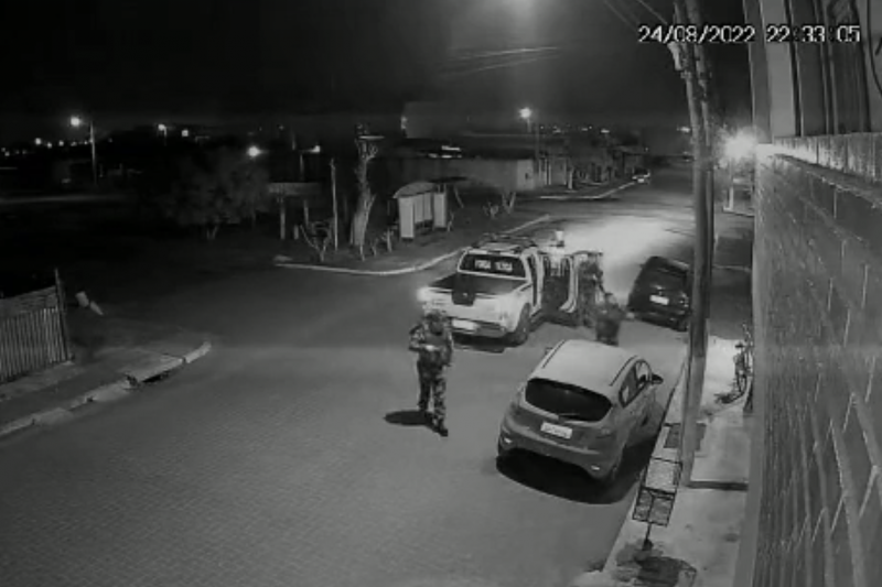 C&acirc;mera de seguran&ccedil;a mostra policiais saindo do carro e indo em dire&ccedil;&atilde;o ao homem.