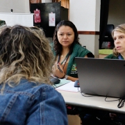 foto de duas servidoras, de frente, atendendo uma assistida que está de costas