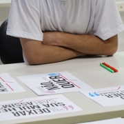 Homem com braços cruzados na mesa de uma sala de aula