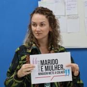 Psicóloga da DPE segurando cartaz usado na dinâmica da oficina