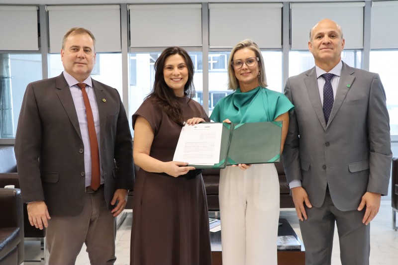 foto dos 4 defensores posados e segurando o termo assinado