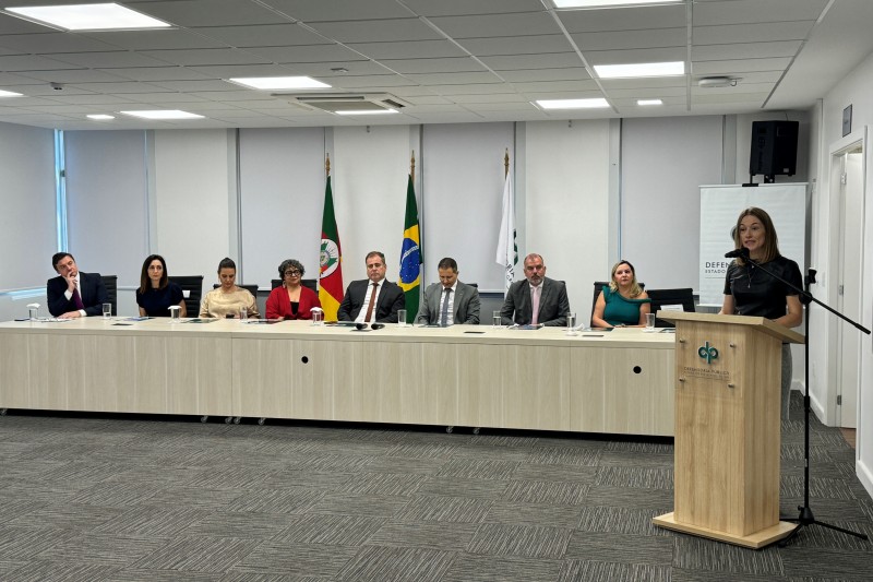 A foto mostra os integrantes da mesa e, &agrave; frente, a convidada da capacita&ccedil;&atilde;o.