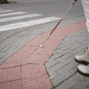 blind person walking through city with blind stick